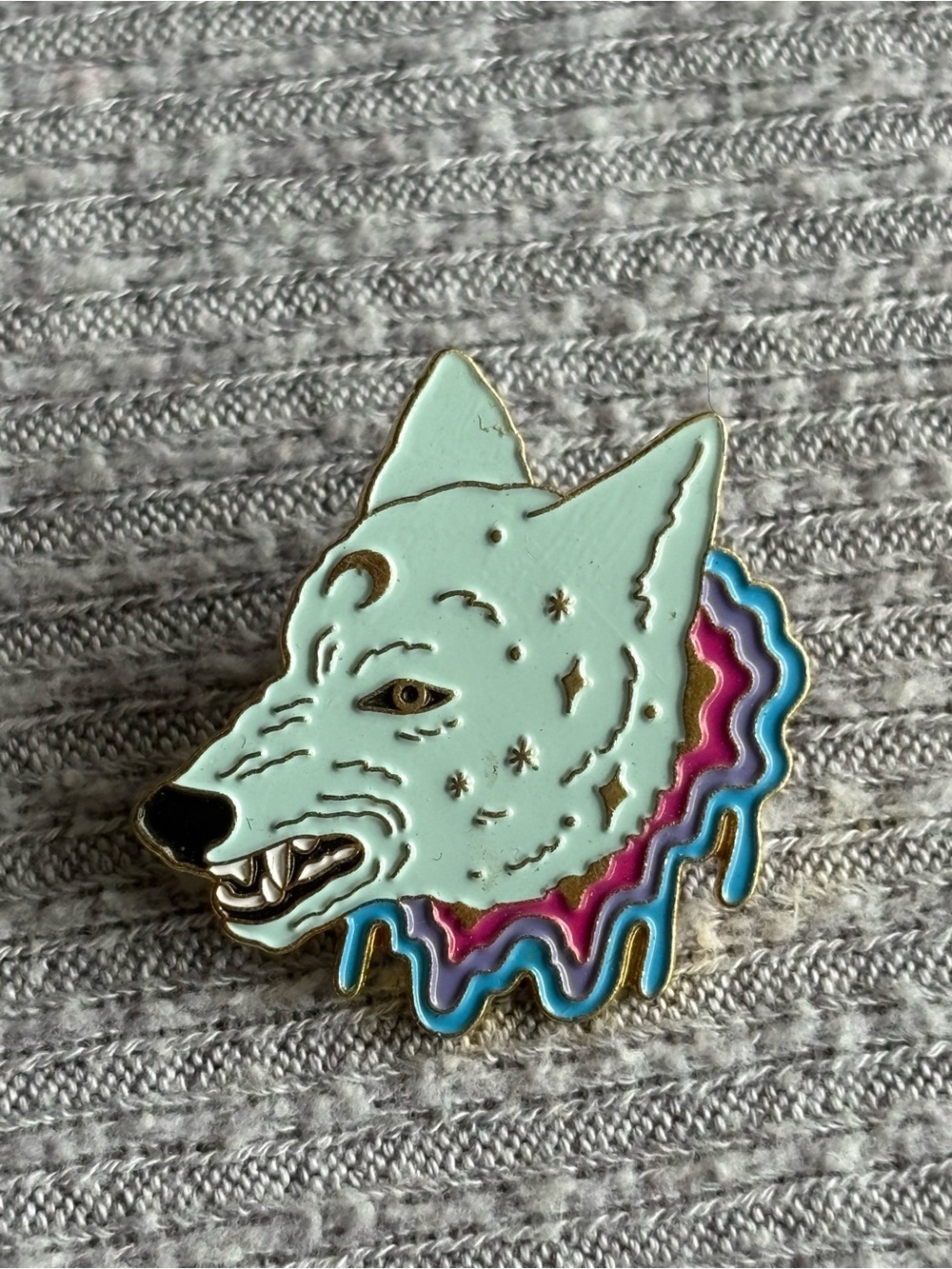 Celestial theme aqua colored snarling wolf popping out of rainbow lapel pin